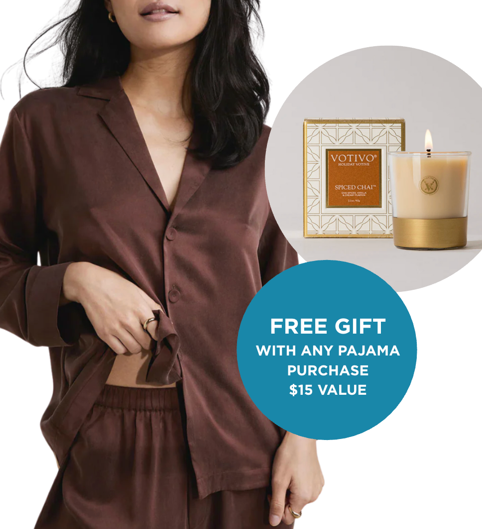 Woman wearing brown silk lunya pajama set with Votivo candle and packaging on a white background