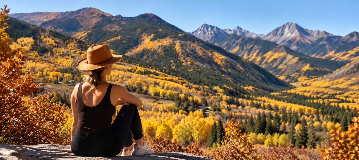 Woman overlooking Colorado mountains and golden aspens in fall