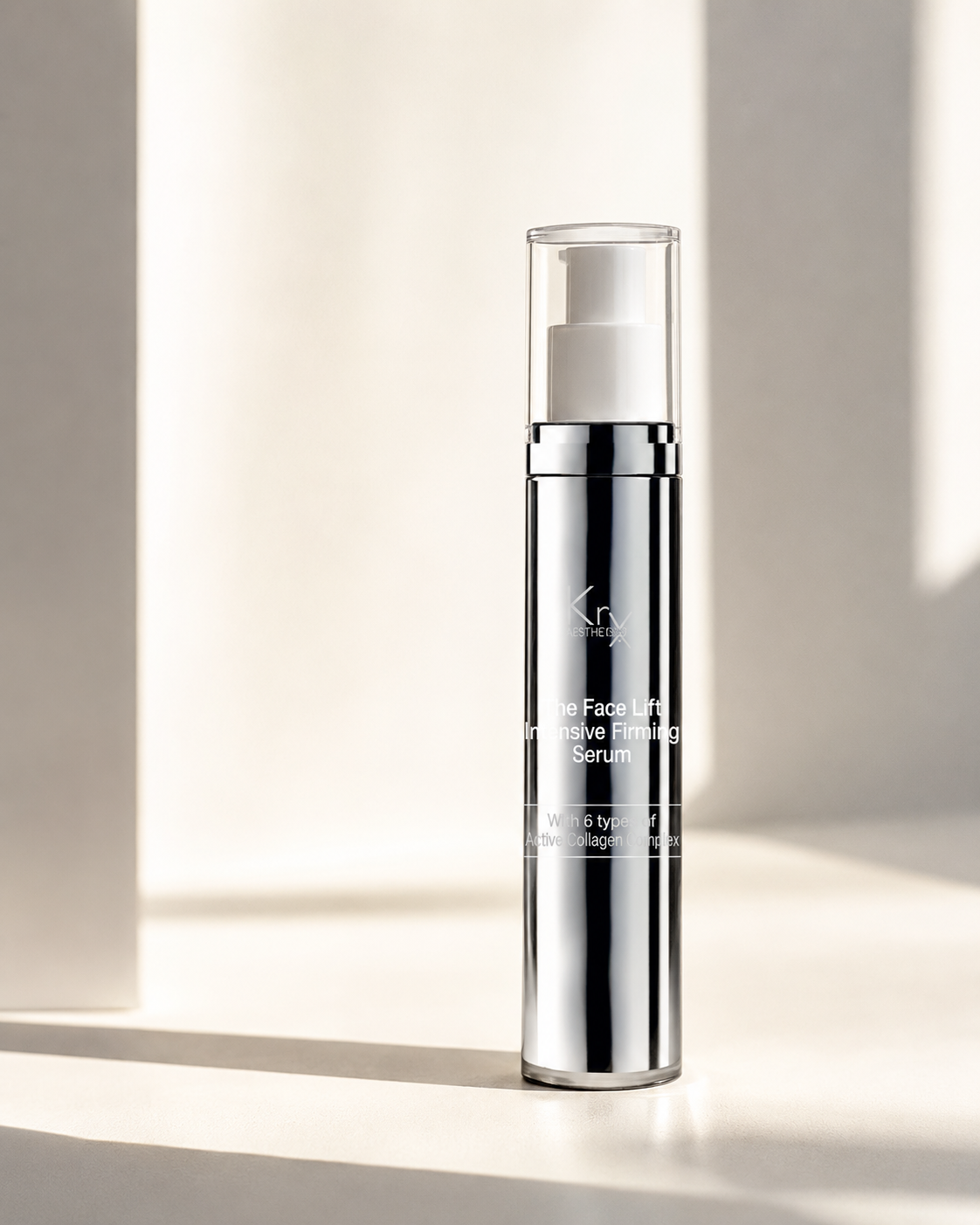 A sleek, cylindrical cosmetic bottle of KrX The Face Lift Intensive Firming Serum, featuring a reflective silver metallic body, a white pump dispenser, and a clear cap, set against a warm, sunlit beige background with soft shadows.