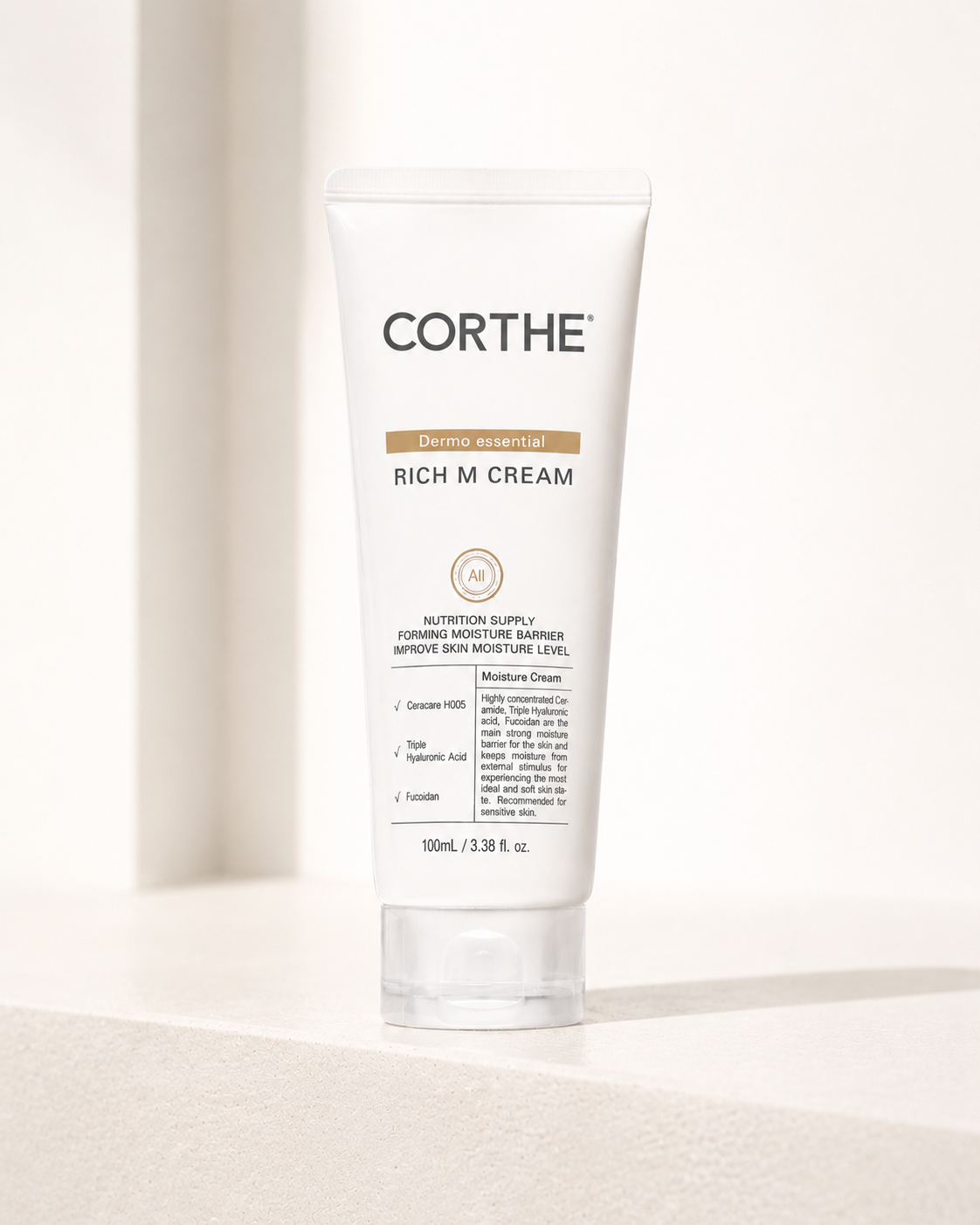 A white tube of Corthe Rich M Cream with a clear cap, standing upright on a light beige surface with a soft shadow.