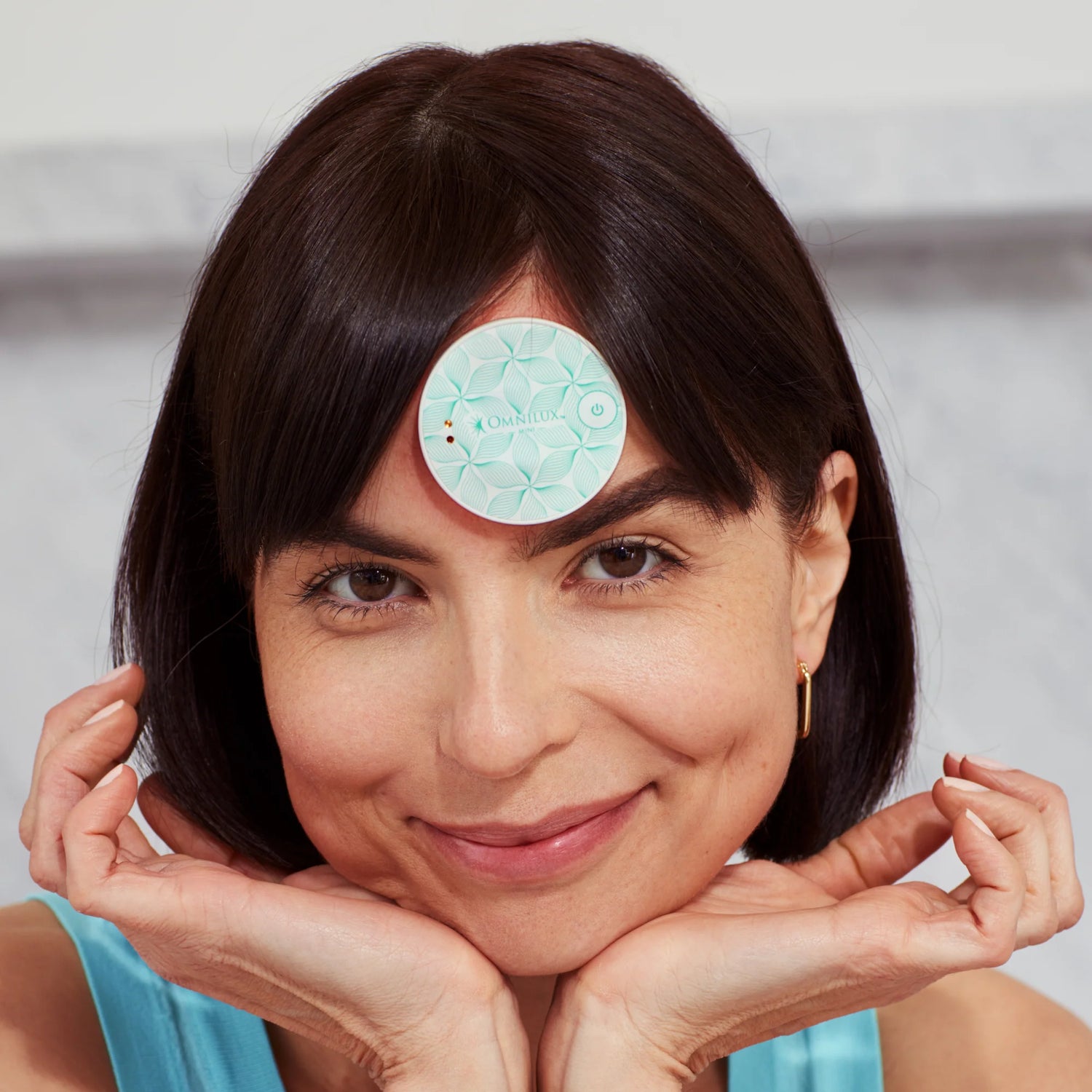 happy woman wearing her omnilux skin corrector on her forehead - get it at heaven on earth 