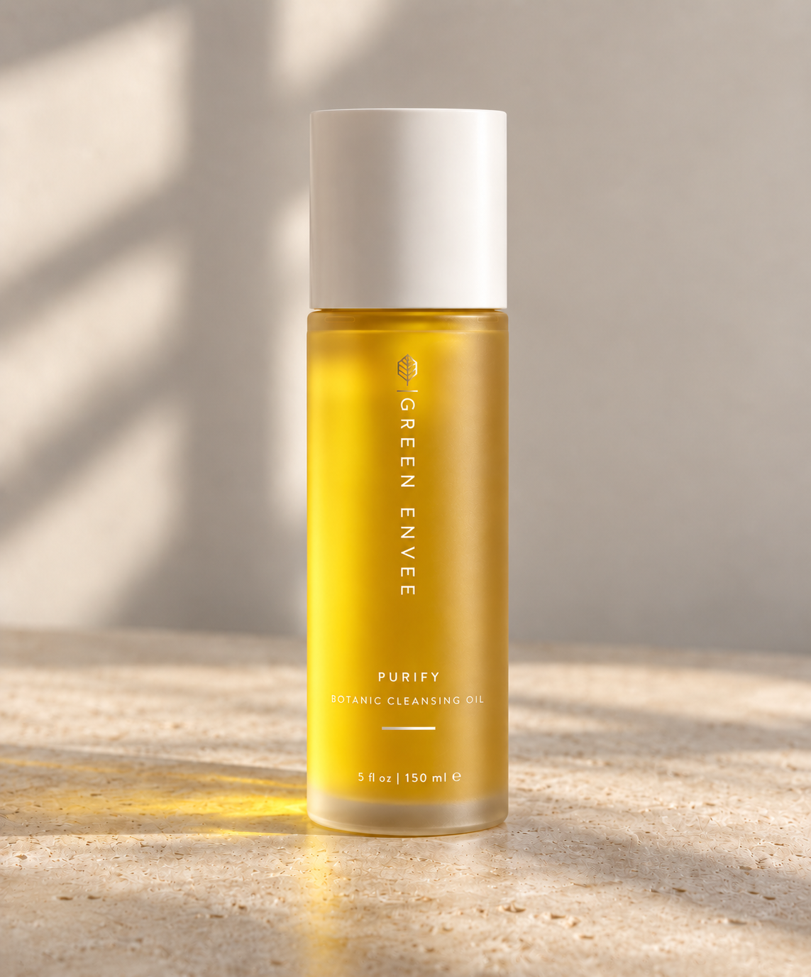 Green Envy Purify Organic Cleansing Oil in a clear bottle showing the golden-yellow oil inside, with a white cap, set on a textured stone surface with soft window shadow lighting.