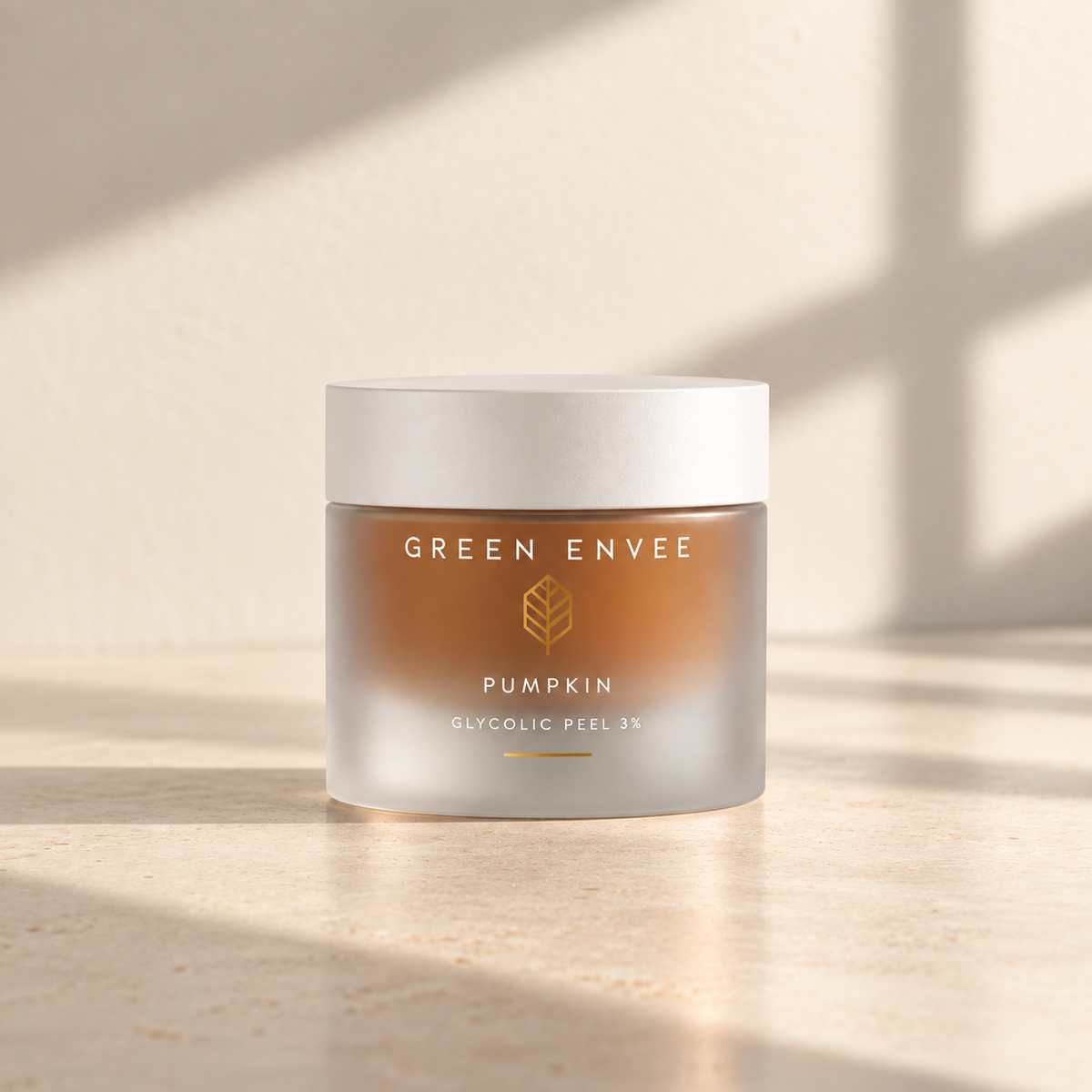 A frosted glass jar of GREEN ENVEE Pumpkin Glycolic Peel 3% containing an amber-brown peel/mask set on a beige stone surface with soft window shadows.