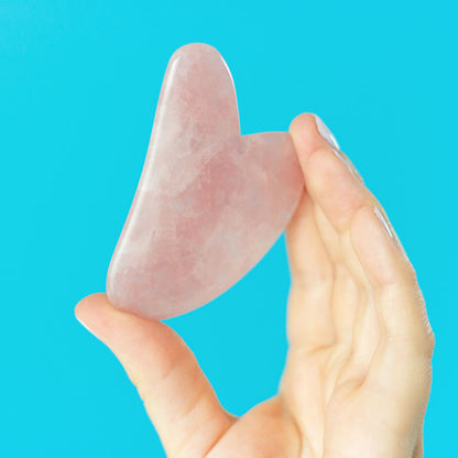 Rose Quartz Gua Sha Stone being held in a hand, sold at heaven on earth aspen