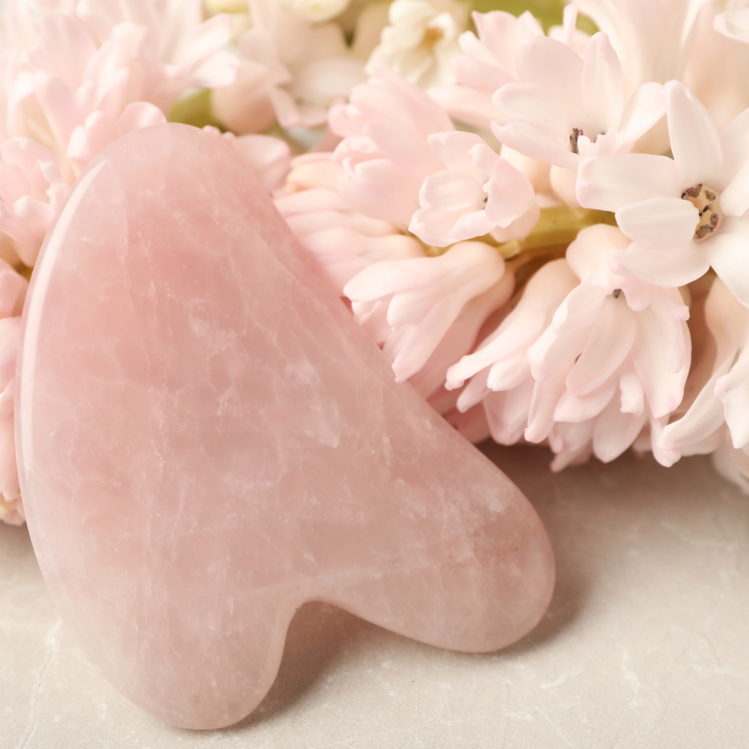 rose quartz gua sha stone with pink flowers - get yours today at heaven on earth aspen