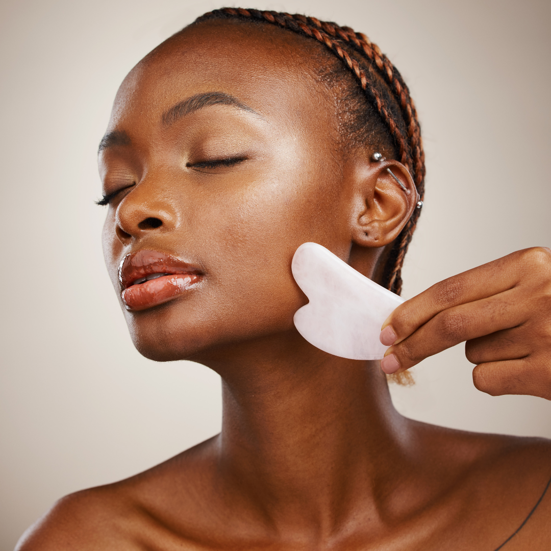 woman holding the rose quartz gua sha stone against her cheek - sold at heaven on earth aspen 