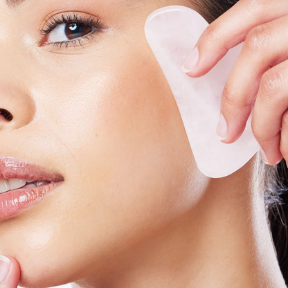 woman holding a gua sha stone against her face available at heaven on earth aspen