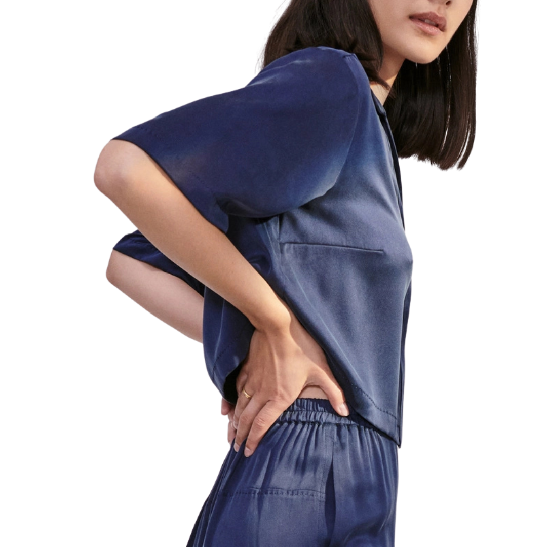 model wearing the cropped top showing the elastic waist of the bottom of the lunya washable silk high rise pant set in deep blue.