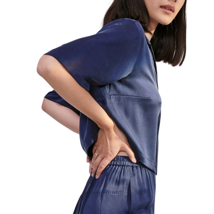 model wearing the cropped top showing the elastic waist of the bottom of the lunya washable silk high rise pant set in deep blue.