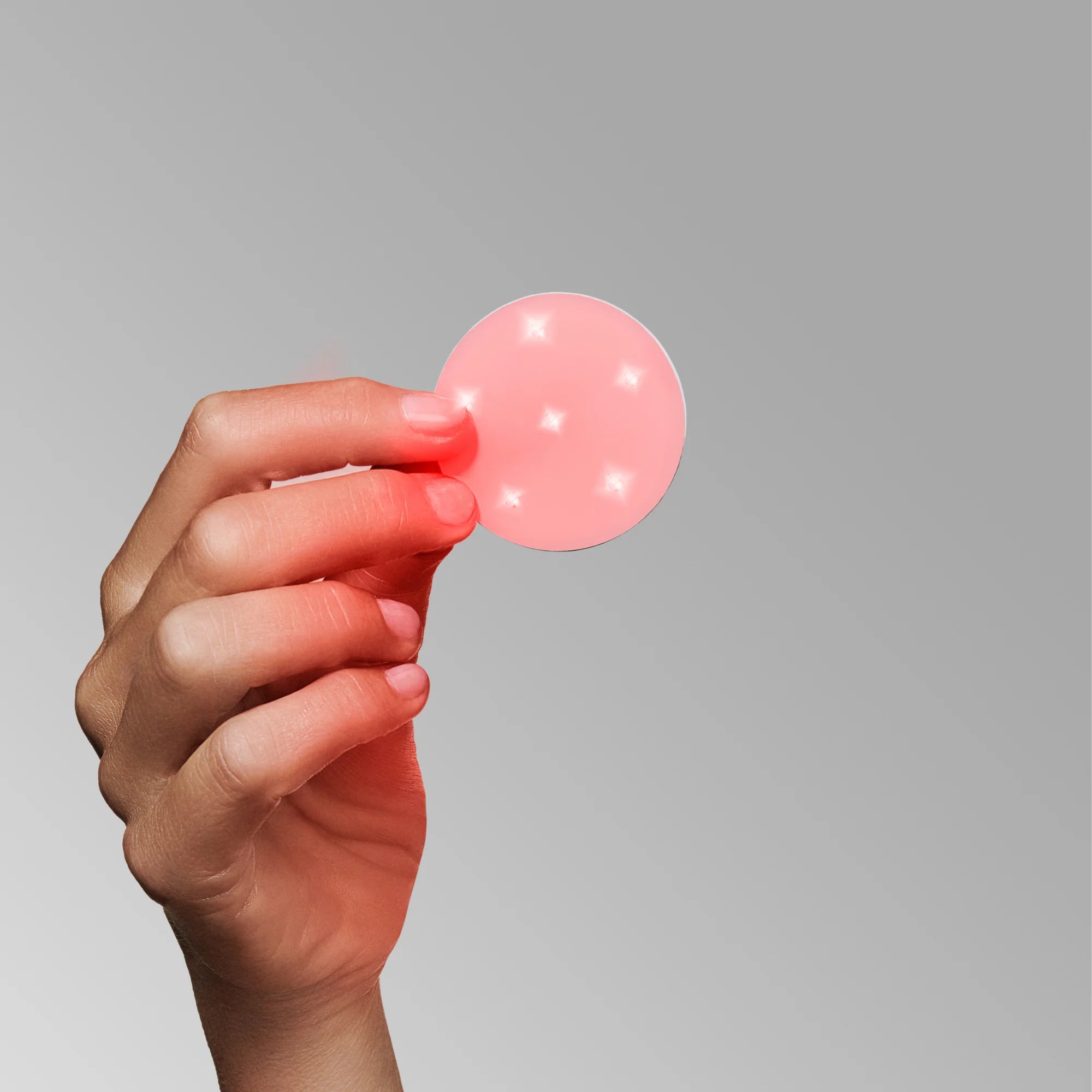 the omnilux mini skin corrector being held in the hand shows the red LED and Infrarard lights