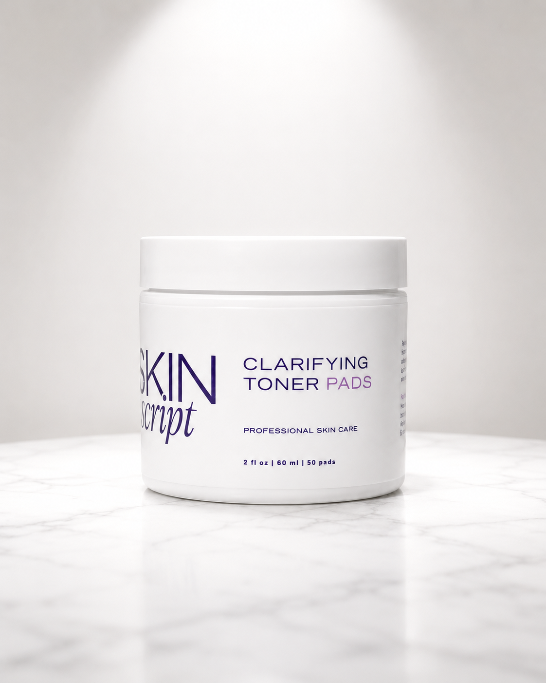 Skin Script Clarifying Toner Pads jar on a white marble surface with soft spotlight.



