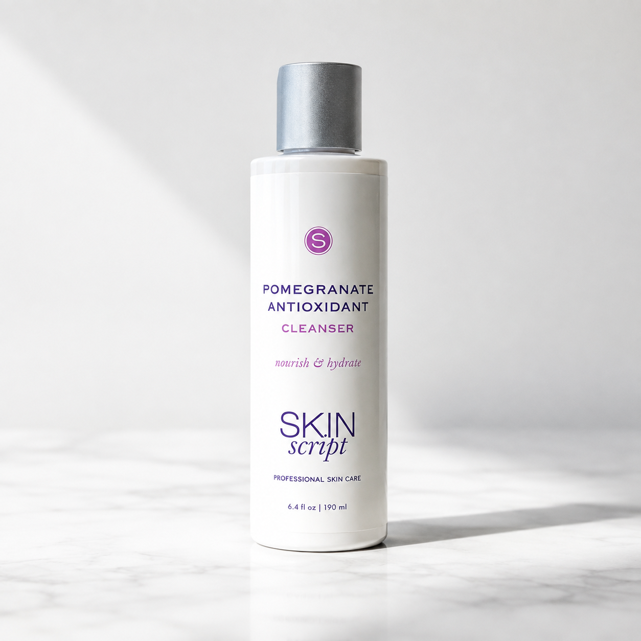 A bottle of Skin Script Pomegranate Antioxidant Cleanser standing on a light marble surface against a white background with soft diagonal shadows.